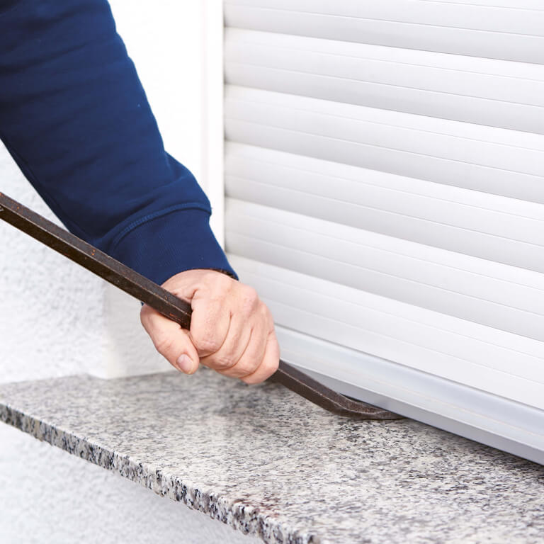 Eine Person bricht in ein Haus ein