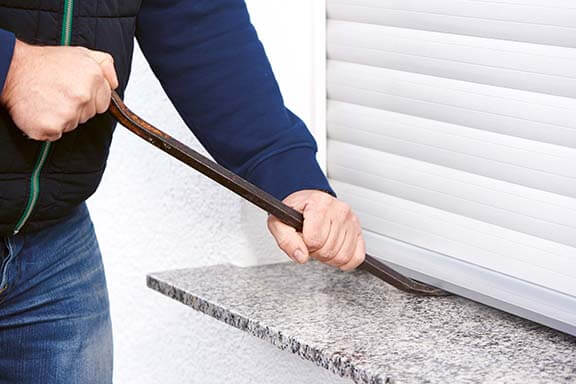 Eine Person versucht ein Fenster aufzubrechen